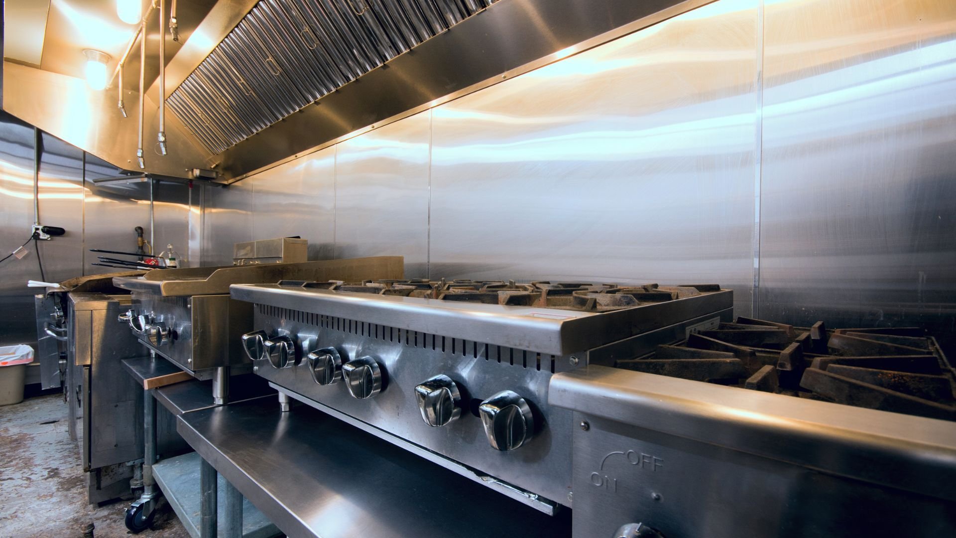 Commercial kitchen with stainless steel stove and industrial exhaust hood