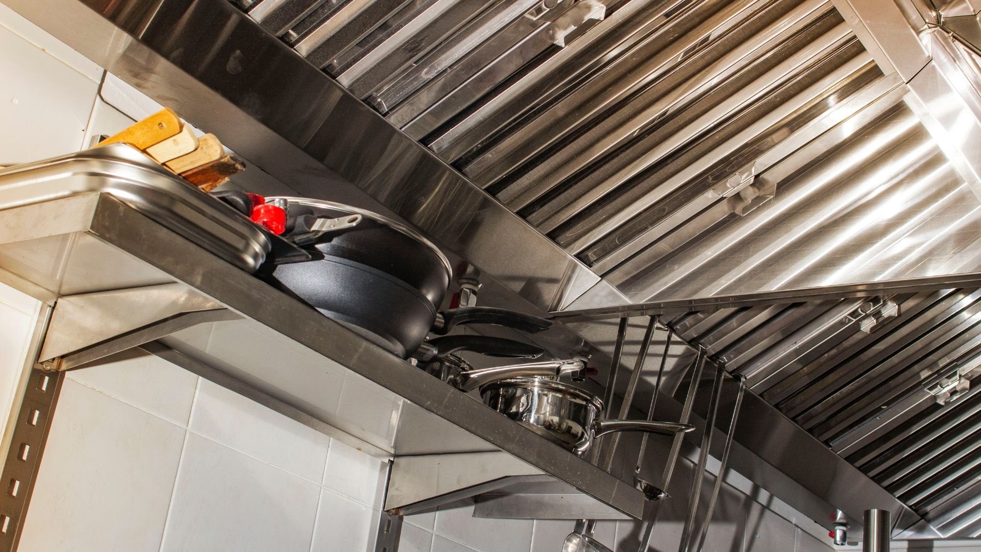 Stainless steel kitchen shelves with pots, pans, and metal ventilation hood