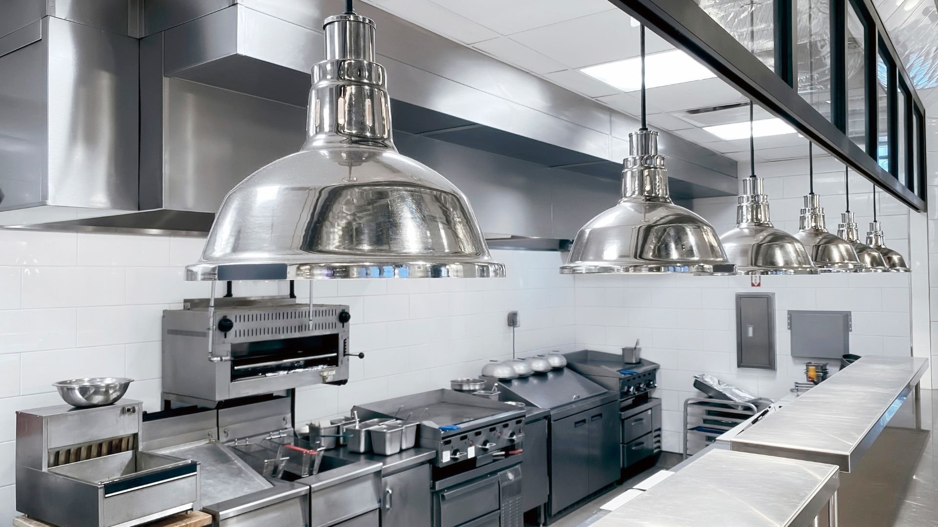 Modern commercial kitchen with stainless steel equipment and hanging lamps