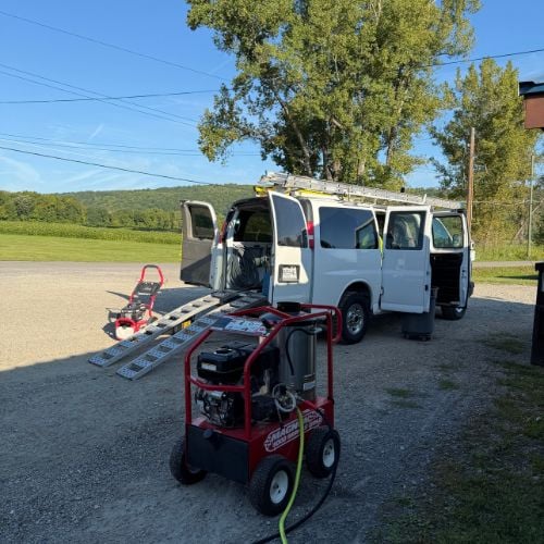 White van with ramps and portable generators parked in rural setting