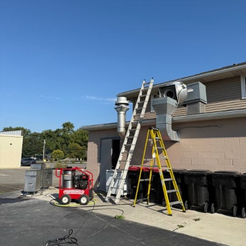 Ladders and generator near building with HVAC equipment on a sunny day